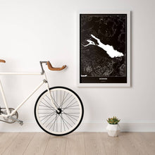 Lade das Bild in den Galerie-Viewer, Bodensee Dark Poster - Minimal - Vorschau in einem hellen Zimmer mit Fahrrad an Wand angelehnt