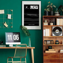 Lade das Bild in den Galerie-Viewer, London City Airport (Flughafen LCY / EGLC) Dark Poster - Minimal - Vorschau über Schreibtisch in einem Zimmer mit grüner Wand und Holzmöbel