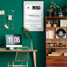 Lade das Bild in den Galerie-Viewer, London City Airport (Flughafen LCY / EGLC) Light Poster - Minimal - Vorschau über Schreibtisch in einem Zimmer mit grüner Wand und Holzmöbel