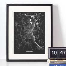 Lade das Bild in den Galerie-Viewer, Magdeburg Dark Poster - Minimal - Vorschau vor weißer Wand zusammen mit Dekoartikeln