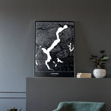 Lade das Bild in den Galerie-Viewer, Langensee Dark Poster - Minimal - Vorschau in einem eleganten Zimmer mit Sessel und grauer Wand
