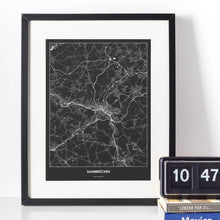 Lade das Bild in den Galerie-Viewer, Saarbrücken Dark Poster - Minimal - Vorschau vor weißer Wand zusammen mit Dekoartikeln
