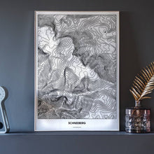 Lade das Bild in den Galerie-Viewer, Schneeberg Light Poster - Minimal - Vorschau neben Dekoartikeln vor dunkelgrauer Wand
