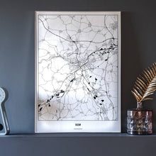 Lade das Bild in den Galerie-Viewer, Ulm Light Poster - Minimal - Vorschau neben Dekoartikeln vor dunkelgrauer Wand
