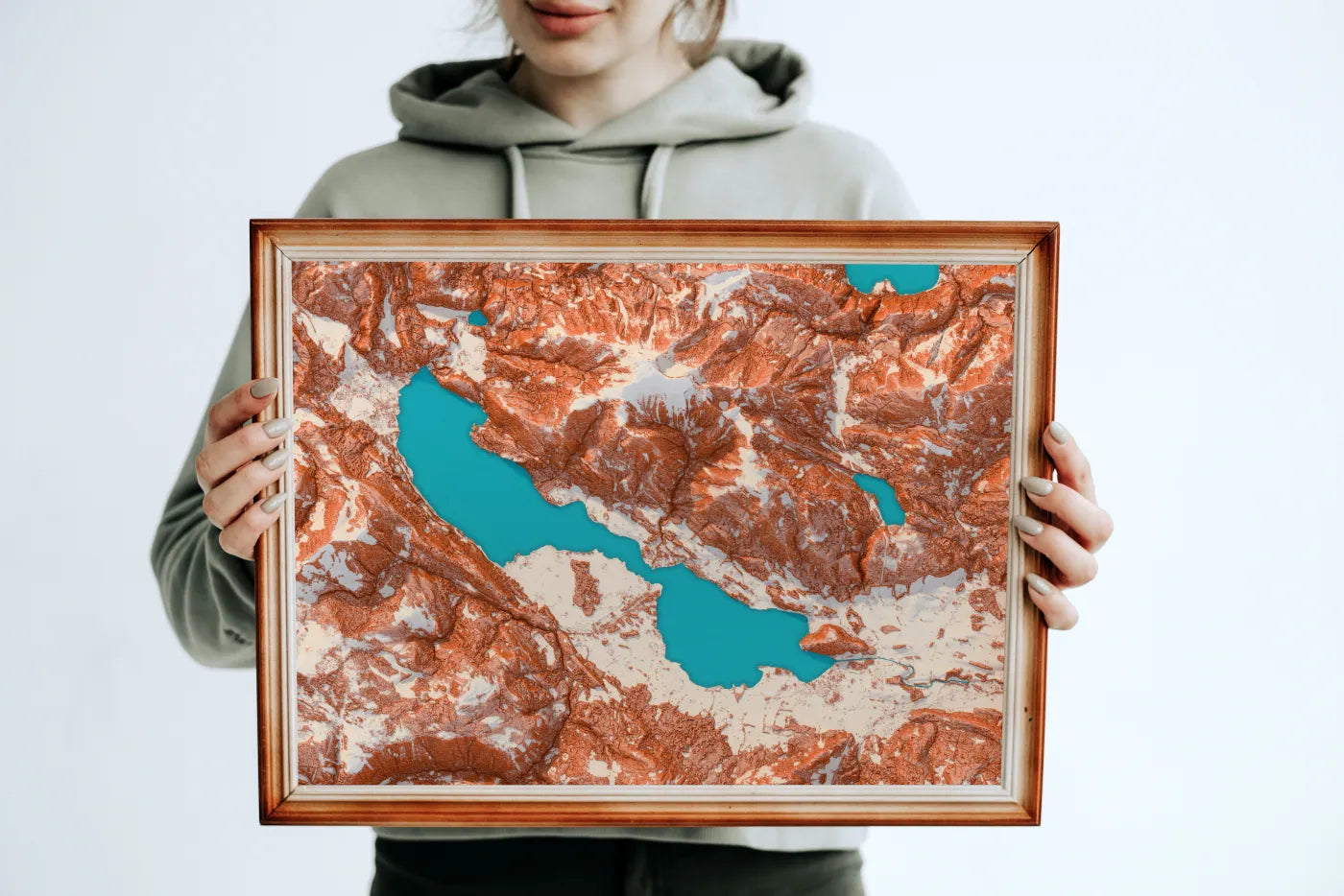 Eine Frau hält ein breites, holzgerahmtes Relief des Wolfgangsees