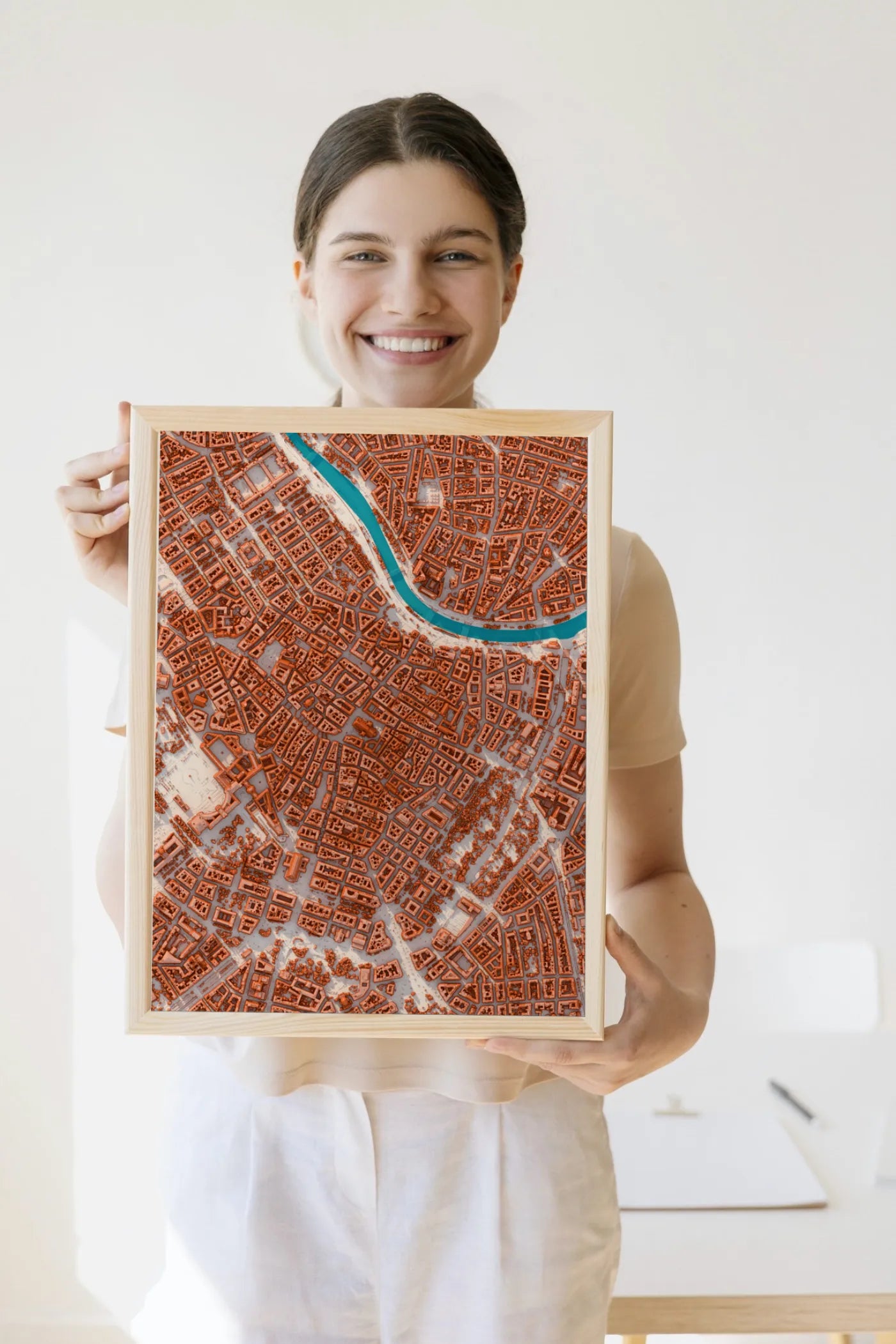 Eine Frau hält ein holzgerahmtes Stadtrelief von Wien im hellen Look